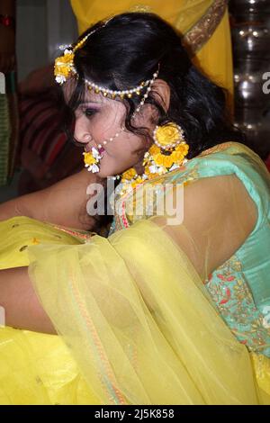 Porträt eines schönen weiblichen Models in gelber Saree mit hellem Make-up und Schmuck aus Blumen. Es ist ein Hochzeitskleid und Make-up der indischen Braut für Stockfoto