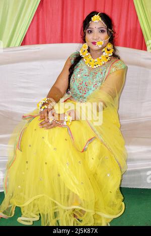 Porträt eines schönen weiblichen Models in gelber Saree mit hellem Make-up und Schmuck aus Blumen. Es ist ein Hochzeitskleid und Make-up der indischen Braut für Stockfoto