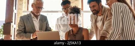 Erfolgreiches Team. Multikulturelles Team am Laptop suchen und etwas diskutieren beim zusammen im modernen Büro arbeiten Stockfoto