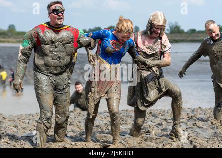 Maldon Promenade Park, Maldon, Essex, Großbritannien. 24. April 2022. Viele Läufer nahmen den zermürbenden Kurs in Angriff, der sie bei Ebbe über den Fluss Blackwater und zurück durch den anhaftende rutschigen Schlamm führte. Die Teilnehmer des Maldon Mud Race laufen für wohltätige Zwecke, viele davon sind in schickem Kleid und alle werden während des Rennens mit schleimigem Schlamm bedeckt, vor allem diejenigen, die hinter sich stehen, sobald der Schlamm aufgewüllt ist Stockfoto