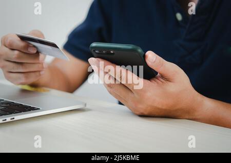 Mann Hand hält Kreditkarte und Handy Online-Shopping E-Commerce und Internet-Banking. Stockfoto