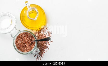Leinöl und Leinsamen in einem Glas auf grauem Grund. Draufsicht, Kopierbereich. Stockfoto