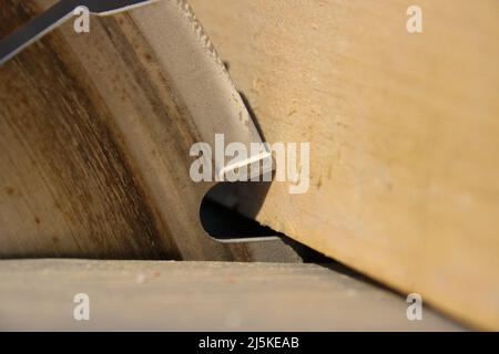 Ein Stück Holz liegt am Sägeblatt einer Kreissäge an Stockfoto