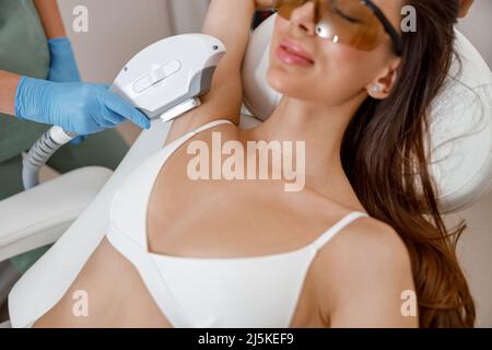 Achselhöhlen-Laserepilation für weibliche Kundin durch modernes Gerät für die Kosmetologie Stockfoto