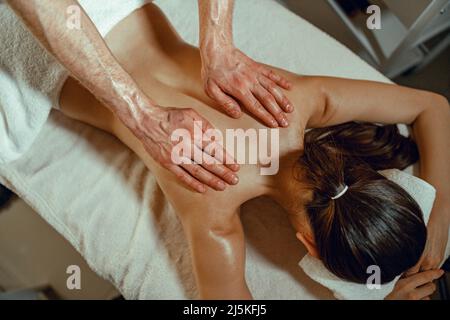 Draufsicht Masseur Mann tut Rückenmassage mit Öl zu einer Frau im Spa-Salon Stockfoto