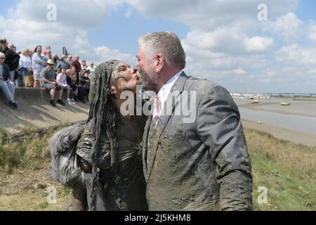 Maldon Essex UK, 24.. April 2022. Matt und Dominique Sellors kamen direkt von ihrer Hochzeit, um im Rennen zu parken. Das Maldon-Schlammrennen kehrt nach zwei Jahren Abwesenheit aufgrund von Covid-19 zum Promenade Park in der Stadt Essex zurück. Das Rennen wird auf einer 450-Meter-Strecke über den Fluss Blackmore ausgetragen und kann nur bei Ebbe stattfinden. Dieses Ereignis entstand im Jahr 1973, als ein Einheimischer aufgefordert wurde, einen Smoking anzuziehen, um eine Mahlzeit am Ufer des Flusses zu servieren. Dies führte später zu einem Rennen über den Fluss, bei dem die Einheimischen ein Pint aus einem wartenden Fass Bier trinken mussten, bevor sie wieder zurückrasen konnten. Bild: Martin Dalton Stockfoto