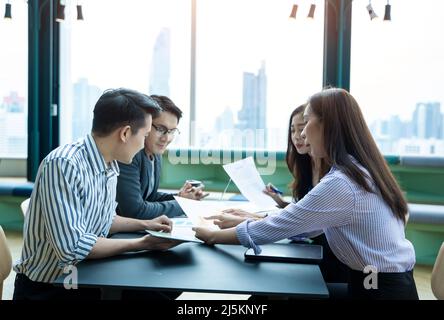 Gruppe von Mitarbeitern, die im Büro interagieren, Mitarbeiter des Geschäftsteams, die beim Treffen Dokumente und Ideen diskutieren. Stockfoto