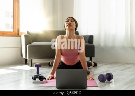 Fitnesstrainer mit virtuellen Yoga-Kurs mit Videoanruf auf Laptop. Remote Yoga Lehrer führt eine Lektion für Menschen Stockfoto