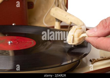 Die Hand eines Mannes senkt den Fuß des Tonabnehmers auf einer Schallplatte in einer Nahaufnahme eines alten Plattenspielers Stockfoto