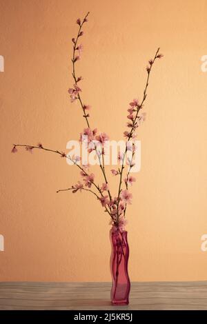 Zweige eines blühenden Pfirsichs in einer Vase auf einem rosa Hintergrund Stockfoto