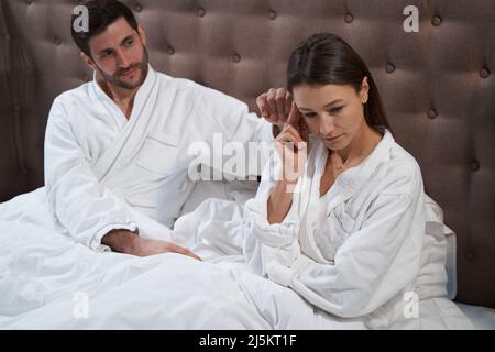 Zornige Frau im Bett, getröstet von ihrem Mann Stockfoto