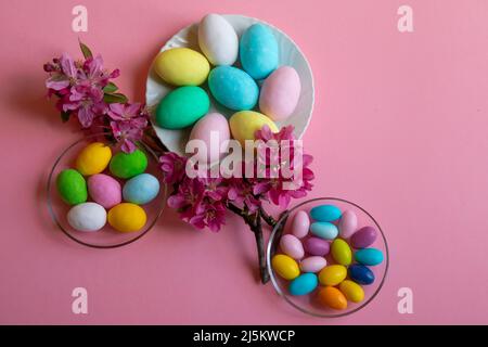 Frohe Ostern! Osterkarte mit einem Bild von farbigen Eiern mit farbigen Eiern von Henne, Taube und Wachtel, verziert mit Blumen auf einem rosa Hintergrund Stockfoto