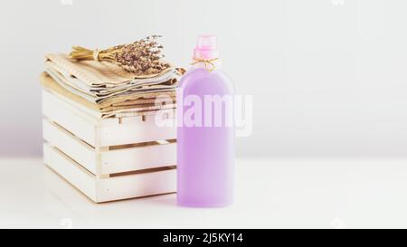 Kunststoffverpackung mit natürlichem Flüssigwaschpulver oder Leinenaufbereiter mit Küchentüchern und Lavendelblüten mit Kopierraum. Nachbau von organischen Stockfoto