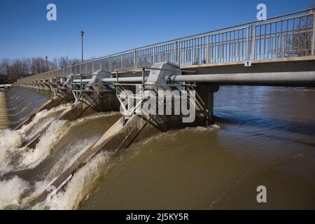 Verschmutztes Wasser, das im Frühjahr durch ein Wasserdurchflusskontrolltor am Fluss Mille-Iles, Lanaudiere, Quebec, Kanada, sprudelt. Stockfoto