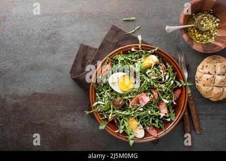 Dandelionensalat mit Eiern und Speck auf grauem Hintergrund Stockfoto