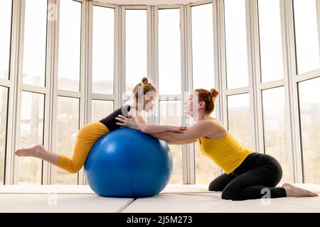 Junge fit Mutter und ihre Tochter Spaß mit Fitness-Ball in der Turnhalle Stockfoto