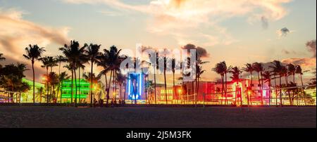 Miami Beach Ocean Drive Panorama mit Hotels und Restaurants bei Sonnenuntergang. Skyline der Stadt mit Palmen bei Nacht. Nachtleben im Art déco-Stil am South Beach Stockfoto