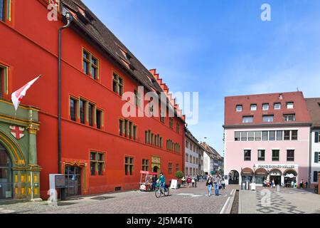 Freiburg, Deutschland - April 2022: Leuchtendes rotes Gebäude der Touristeninformation am Rathausplatz Stockfoto