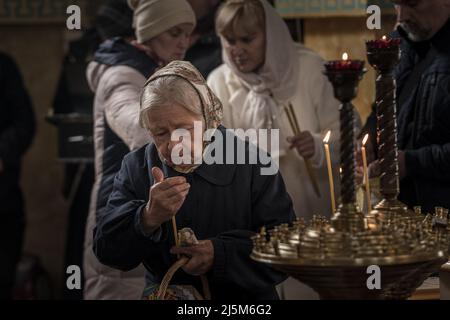 Irpin, Ukraine. 24. April 2022. Eine Frau trägt eine Kerze, als sie am Sonntag, dem 24. April 2022, in der Kirche des heiligen Nikolaus, des Wundertäters der Ukrainischen Orthodoxen Kirche in Irpin, Ukraine, Ostergottesdienste besucht. Der Generalsekretär der Vereinten Nationen, António Guterres, wird am Dienstag in Moskau mit dem russischen Präsidenten Wladimir Putin und dem russischen Außenminister Sergej Lawrow zusammentreffen. Foto von Ken Cedeno/UPI Credit: UPI/Alamy Live News Stockfoto