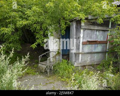 Ein Korbsessel am Eingang zu einem alten verlassenen ländlichen Haus. Stockfoto