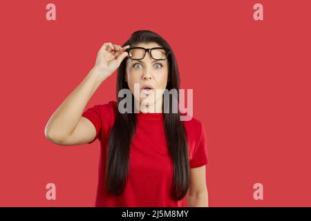 Junge Frau, die etwas mit einem überraschenden, schockierten, erstaunten Gesichtsausdruck anschaut Stockfoto