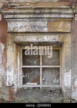 Das Fenster eines alten Hauses, das von den Bewohnern aufgrund der Gefahr eines weiteren Wohnsitzes verlassen wurde. Stockfoto