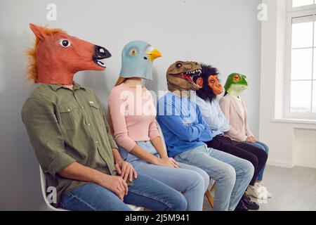 Verschiedene Menschen in Tiermasken in Reihe im Büro Stockfoto