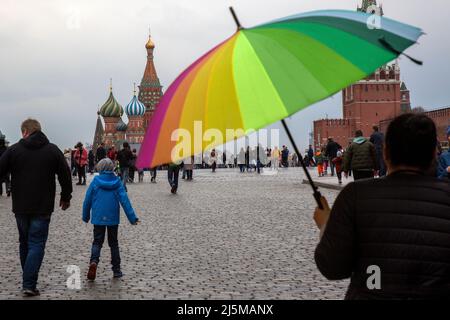 Moskau, Russland. 24.. April 2022. Regnerisches Wetter in Moskau. Eine Frau mit bunten Regenschirmen geht auf dem Roten Platz im Hintergrund der Basilius-Kathedrale im Zentrum von Moskau, Russland Stockfoto