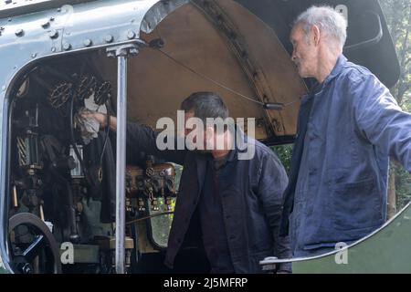 Fahrer und Feuerwehrmann, die die Steuerung im Fahrerhaus der Dampflokomotive der Klasse 30925 Schools, die auf der traditionsreiche Watercress Line fährt, untersuchen. Hampshire Stockfoto