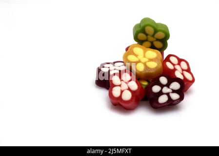 Nahaufnahme von bunten, rot-gelb-grünen Gummibonbons, übereinander gestapelt und nebeneinander in Blütenform mit weißen Punkten auf weißem Hintergrund Stockfoto