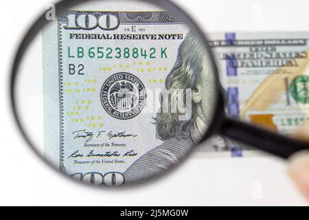 Finanzen und Unternehmen. Nahaufnahme mit einer Lupe über 100-Dollar-Banknoten. Inspektion eines Hundert-Dollar-Bill Stockfoto