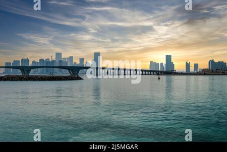 Abu Dhabi, Vereinigte Arabische Emirate - Februar 2022: Panorama-Skyline von Abu Dhabi mit einer Brücke bei Sonnenuntergang. Abu Dhabi zieht 10 Millionen Menschen an Stockfoto