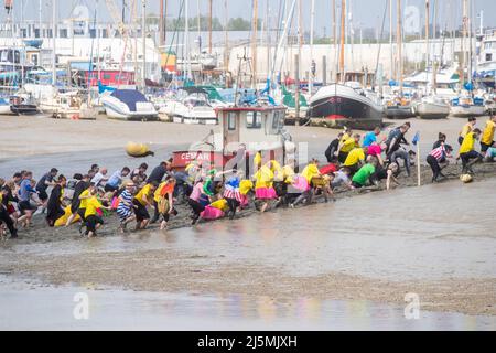 Essex, Großbritannien. 24. April 2022. Die Teilnehmer nehmen am Maldon Mud Race in Maldon, Essex, Teil, da das Rennen zum ersten Mal seit zwei Jahren zurückkehrt. Das Maldon Mud Race ist ein alljährliches Fun-Rennen, das im Frühjahr (ursprünglich im Winter, jetzt Ende April oder Anfang Mai) im Promenade Park in Maldon, Essex, England, stattfindet und bei dem die Teilnehmer um einen 500 Meter (550 Meter) langen Schuss in dickem Schlamm kämpfen. Über dem Bett des Flusses Blackwater. Das Rennen wird von den Lions & Rotary Clubs von Maldon und dem Maldon District Council organisiert, die Geld für wohltätige Zwecke sammeln. Kredit: SOPA Images Limited/Alamy Live Nachrichten Stockfoto