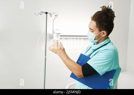 Medizinisches Personal, das die Flasche in das IV-Tropf-Gerät setzt Stockfoto