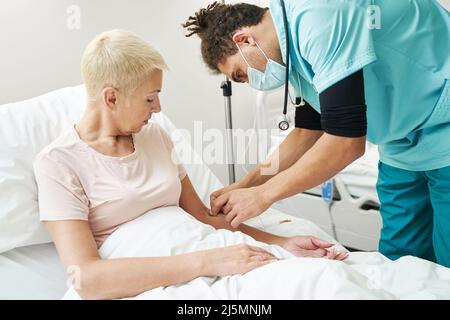 Medizinische Person, die Nadel der IV-Linie in den Frauenarm einführt Stockfoto