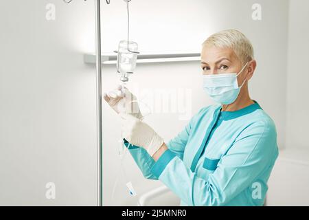 Ärztin, die medizinische Flüssigkeit in die Infusionsflasche einführt Stockfoto