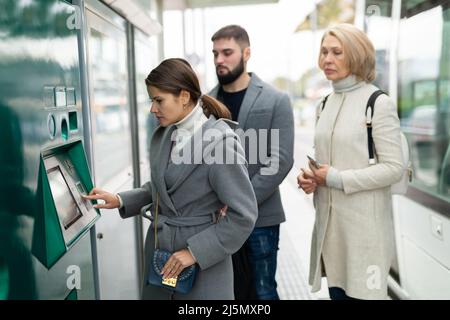 Junge Frau, die den Ticketautomaten benutzt Stockfoto