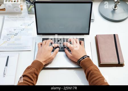 Blick aus der Perspektive eines Geschäftsmannes, der während der Arbeit an einem neuen Webprojekt auf dem Laptop tippt Stockfoto