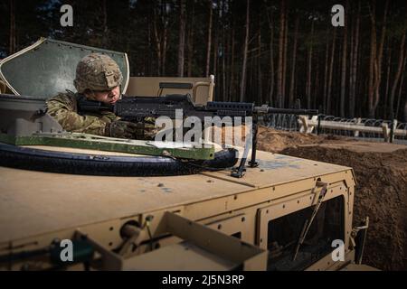 Ein Soldat, der dem Truppenschutzzug (FPP), dem Bataillon 3., dem Panzerregiment 66., dem Kampfteam der 1. Panzerbrigade, der Infanteriedivision 1., zugewiesen ist, sorgt während einer Torläuferübung, die am 13. April 2022 im litauischen Lager Herkus durchgeführt wurde, für die Perimetersicherheit von der Spitze eines Humvees. Im Rahmen der Schulung mussten die Mitglieder des FPP ein verdächtiges Fahrzeug identifizieren und darauf reagieren, das verdächtigt wurde, seinen Eintritt in die Einrichtung zu erzwingen. Die 1. Infanterie-Division ist unter anderem dem V-Corps zugeordnet, dem amerikanischen Vorwärtskorps in Europa, das mit NATO-Verbündeten und regionaler Sicherheit zusammenarbeitet Stockfoto