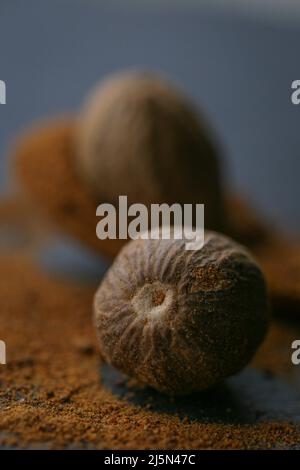 Muskatnuss und Muskatpulver in einem Löffel auf Schiefergrund.Gewürze und Gewürze.Muskatnuss Nahaufnahme auf dunklem Hintergrund. Dunkle Stimmung. Stockfoto