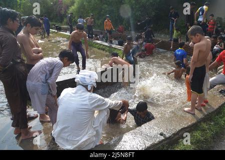 Lahore, Punjab, Pakistan. 24. April 2022. Pakistanische Jugendliche genießen ein Bad im Kanalwasser, um der Hitze zu entlasten und sich von dem warmen Wetter in Ramazan-ul-Mubarak in Lahore zu entlasten. (Bild: © Rana Sajid Hussain/Pacific Press via ZUMA Press Wire) Stockfoto