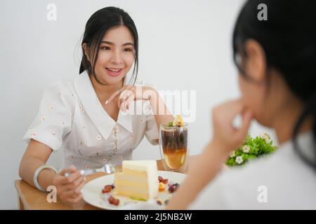Millennial Lifestyles Konzept. Zwei Millennials-Frauen genießen es, Desserts zu essen und im Café zu plaudern. Stockfoto