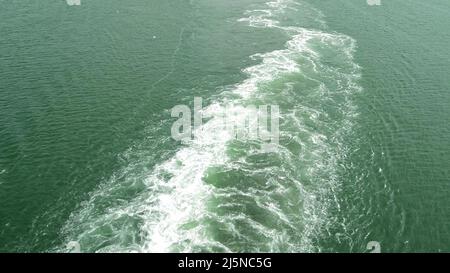 Eine schäumende, sprudelnde Spur auf der blauen Wasseroberfläche durch die Bewegung eines großen Schiffes auf See Stockfoto