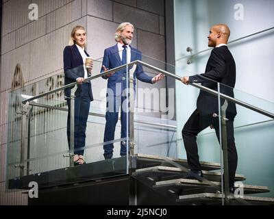 kaukasischer Geschäftsmann und Geschäftsfrau begrüßen Latino-Kunden im modernen Bürogebäude Stockfoto