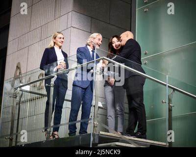 kaukasische asiatische und latino-Geschäftsleute treffen sich im modernen Bürogebäude und sprechen sich dabei die Hände schüttelnd an Stockfoto