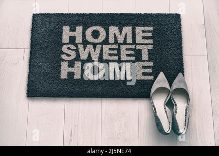 Neue Wohnung vor der Tür Matte Blick von oben. Modern living Business Frau High Heel Schuhe auf Home Sweet Home Eingang Fußmatte. Hausbesitzer Umzug in Konzept Stockfoto