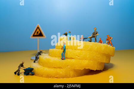 Mini-Bauleute arbeiten an einer Ananas. Schneiden und Schneiden. Stockfoto