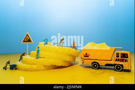 Mini-Bauleute arbeiten an einer Ananas. Schneiden und Schneiden. Stockfoto