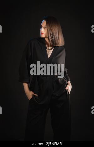 Studio Aufnahme der Brünette Frau 30s trägt schwarzen Seide Pyjamas. Stockfoto