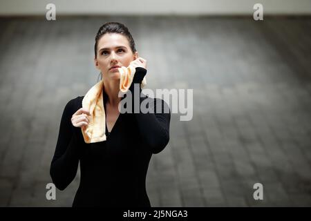 Porträt einer müden jungen Sportlerin, die nach dem Joggen oder dem Training mit einem Handtuch den Schweiß abwischt Stockfoto